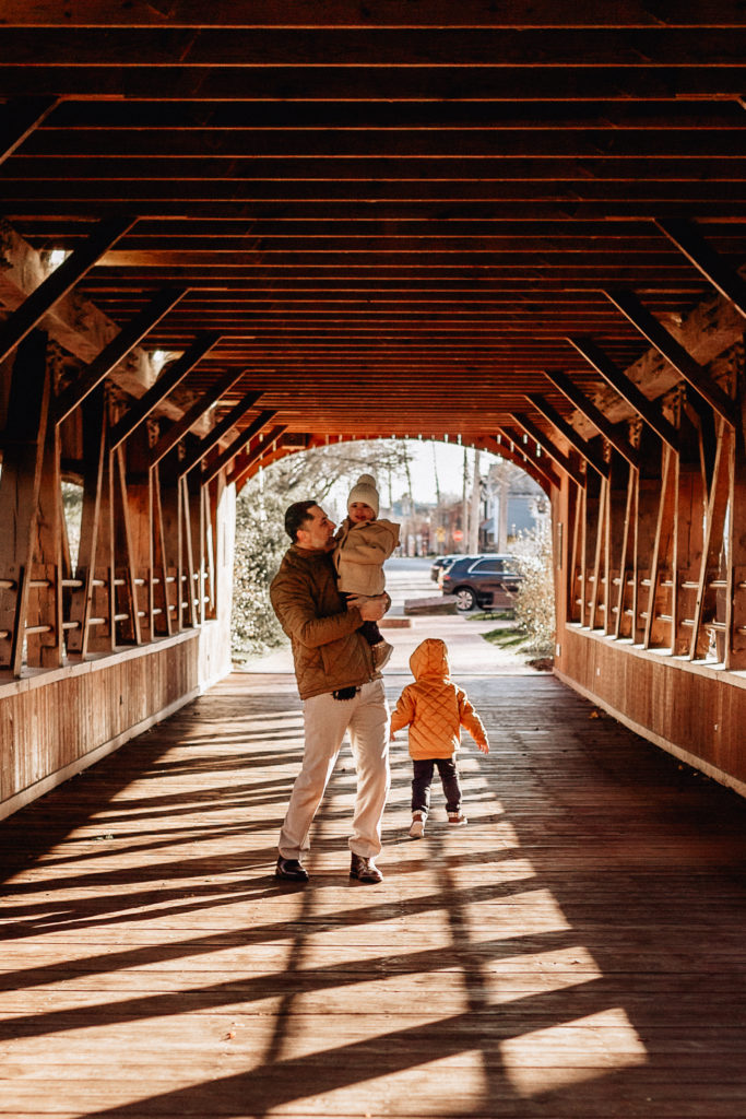 dad under a covered bridge having fun with his two sons
