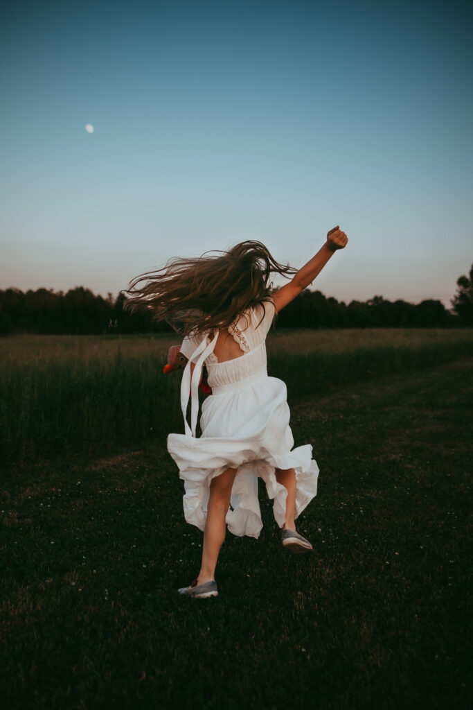 little girl jumping and running with the moon behind her
