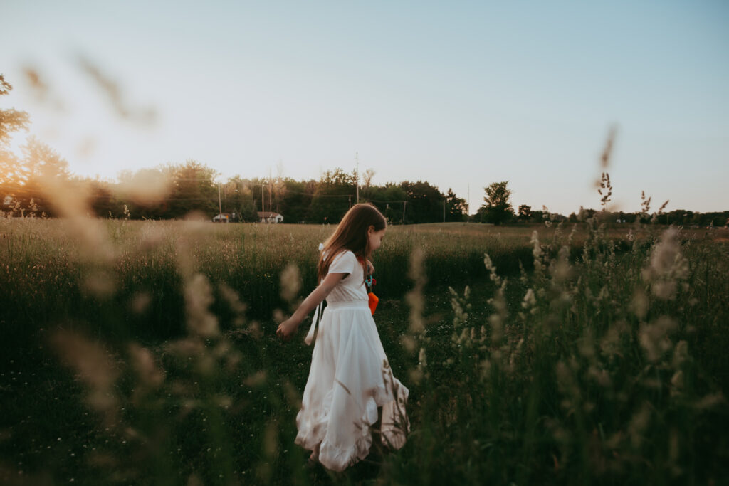 girl walking through a field of tall grass