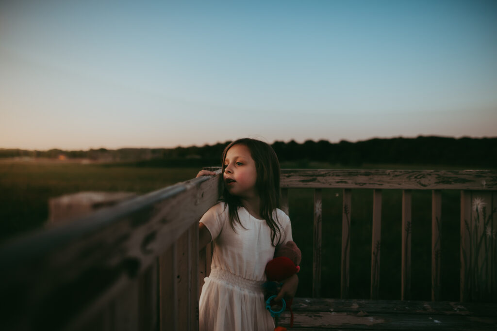 little girl looking over a fence rail
