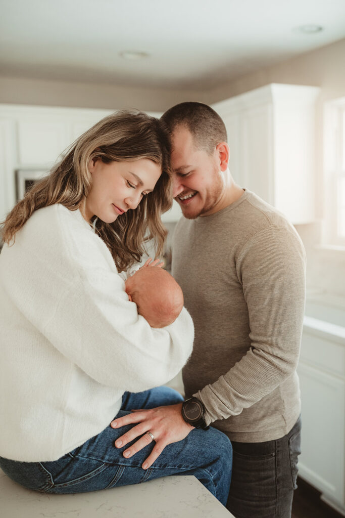 mom sitting on kitchen counter, holding newborn with dad