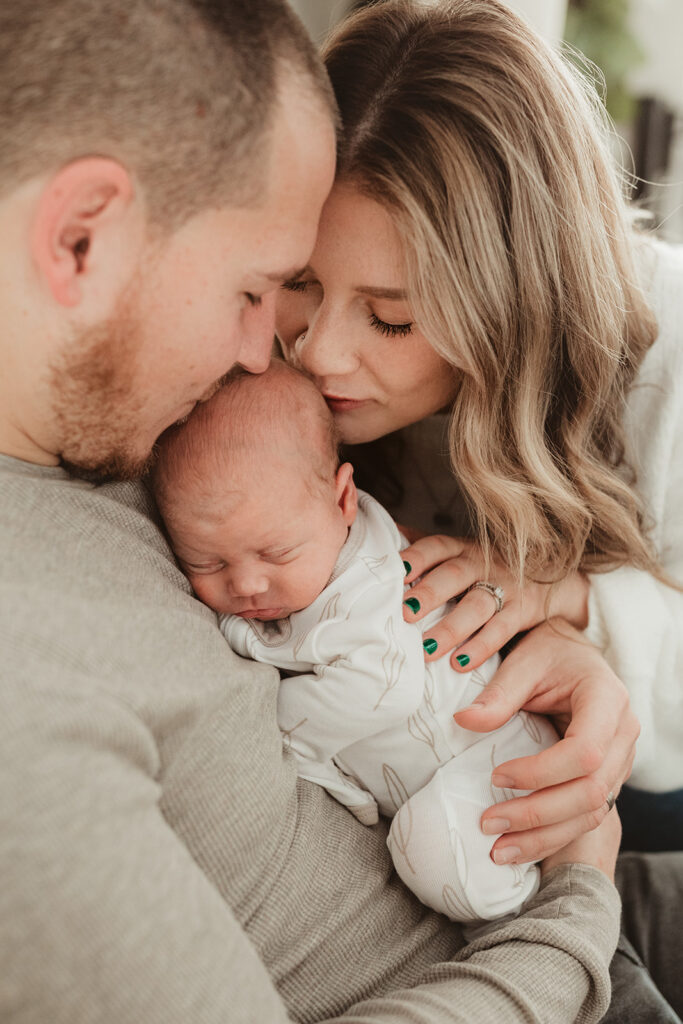 mom and dad snuggling baby boy
