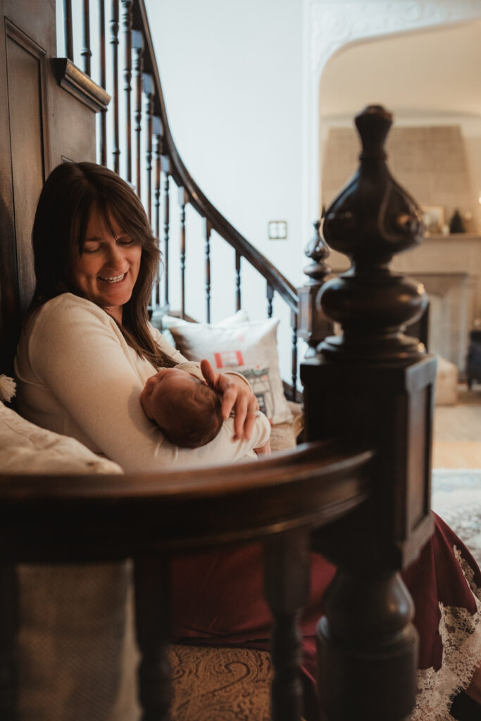 mom snuggles newborn alone in a cozy place by the staircase