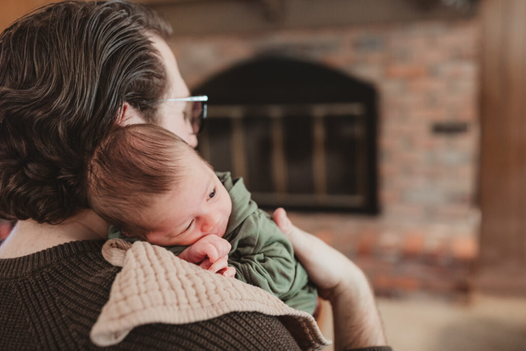 newborn snuggled on dads shoulder