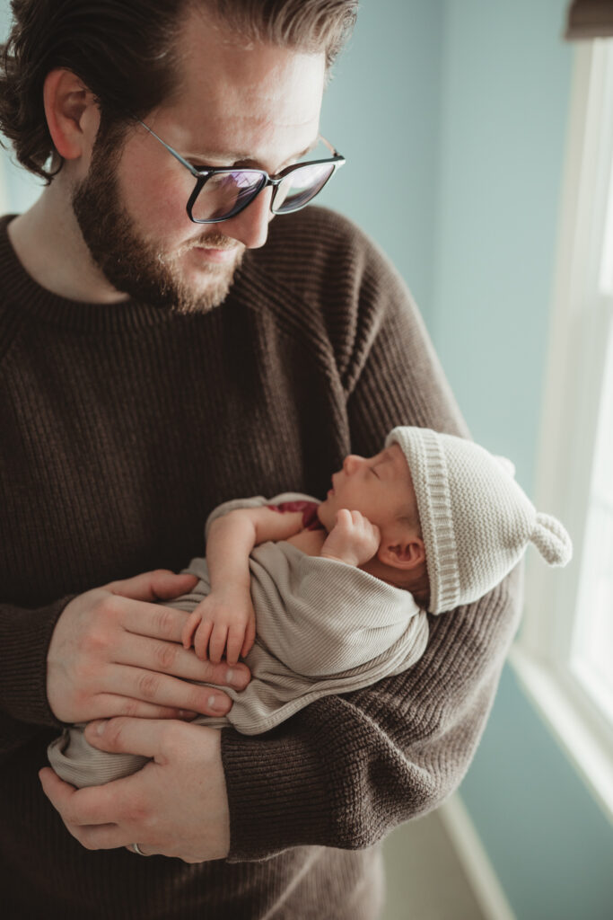 dad looking down at baby boy. baby boy has a birthmark on his shoulder.