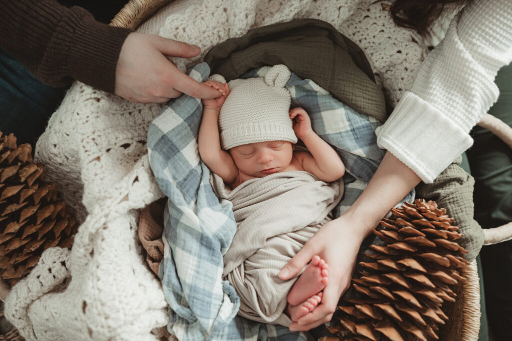 close up of dad holding baby's hand, and mom holding baby's foot.