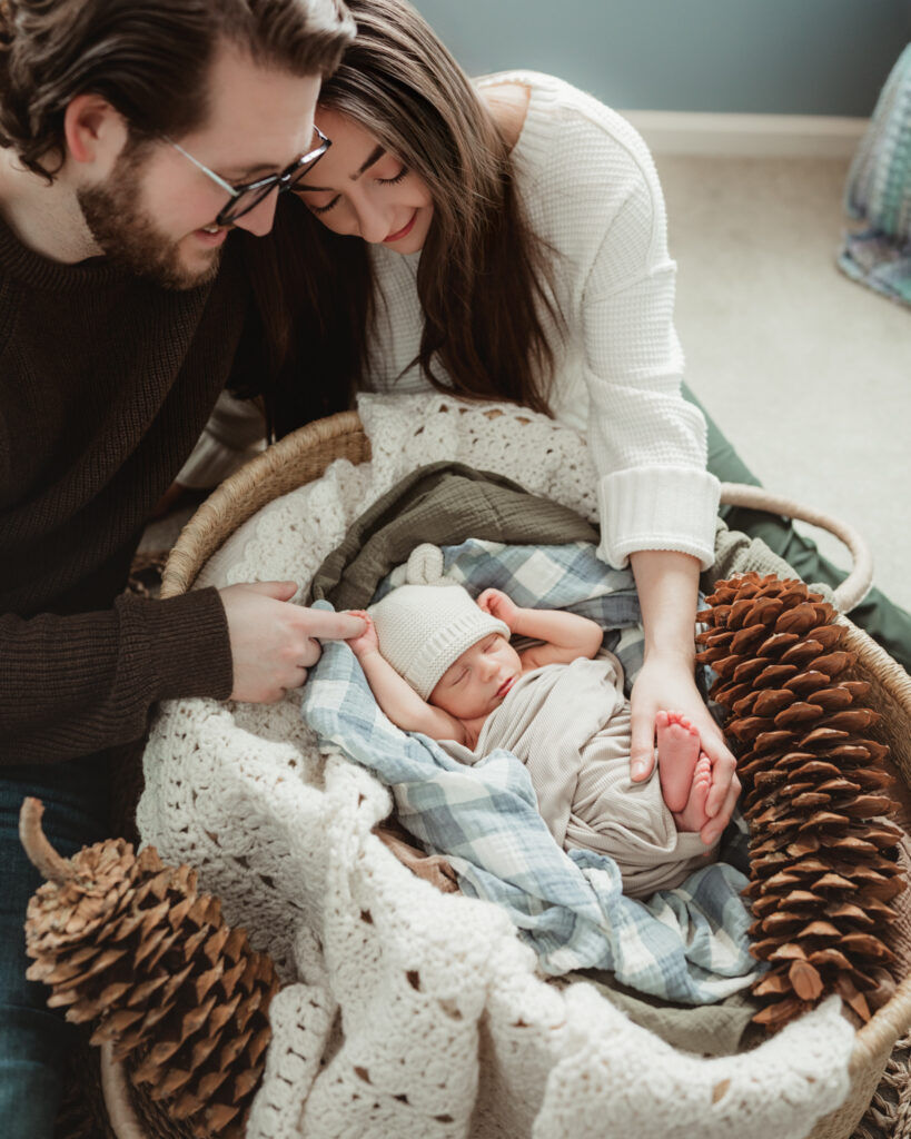 mom and dad snuggled together while they hold their baby in the basket.