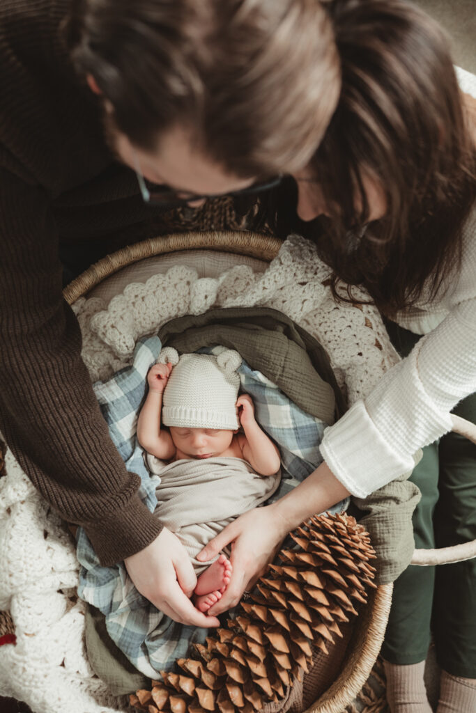 above shot of mom and dad looking down at their baby in the basket.