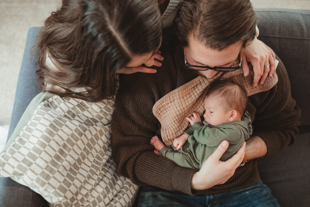 shot from above as mom and dad look down at baby held against dads chest