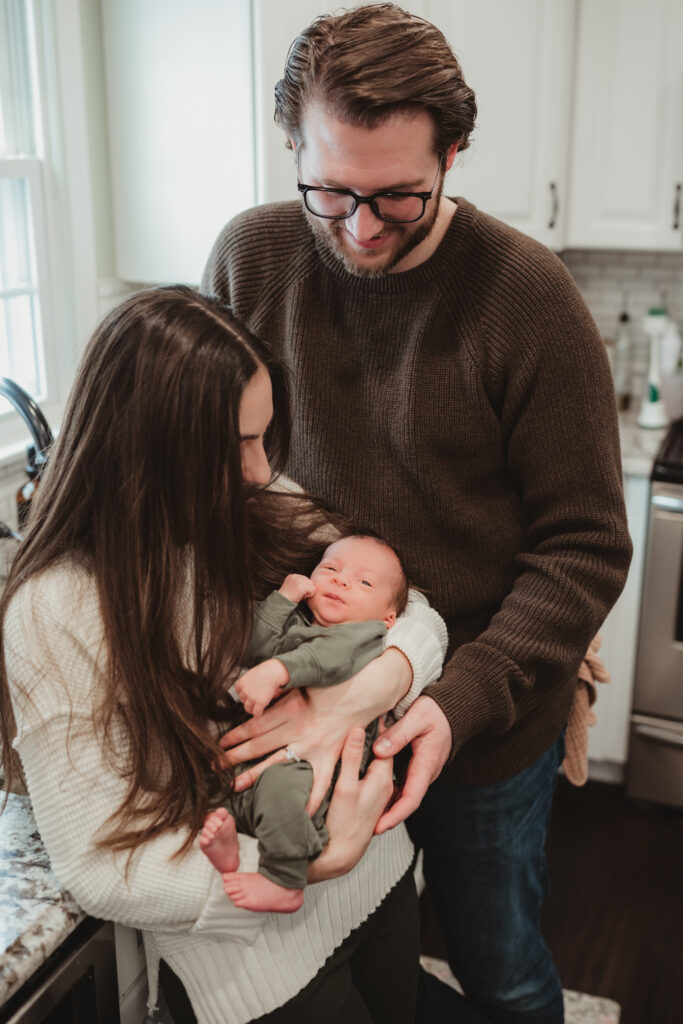 mom and dad snuggle baby in the kitchen