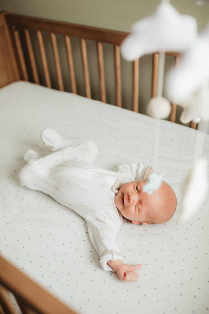 baby in his crib with cloud and stars mobile
