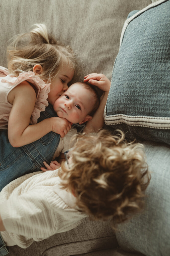 little sister kisses baby on the cheek
