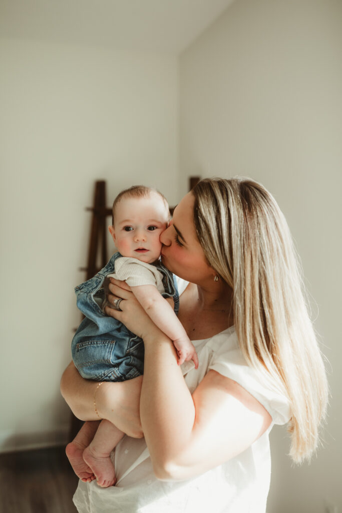 mom holds baby and kisses his cheek