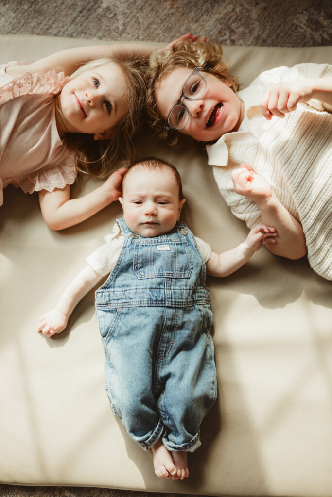 all three kids laying down with baby