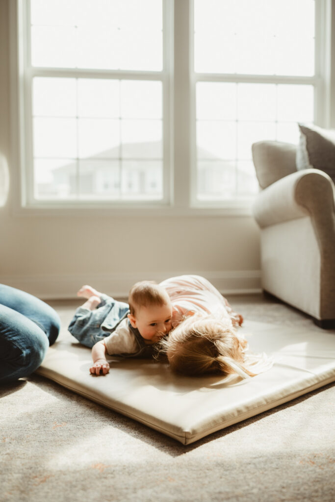 little sister snuggles baby on the floor