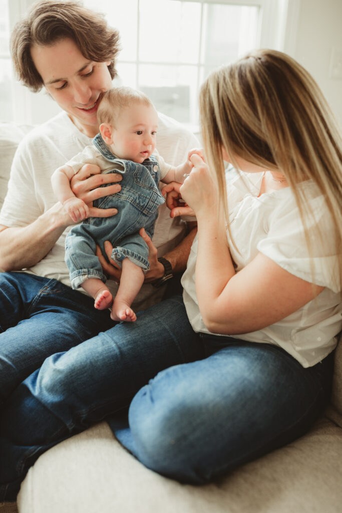 mom and dad hold and snuggle baby on the couch