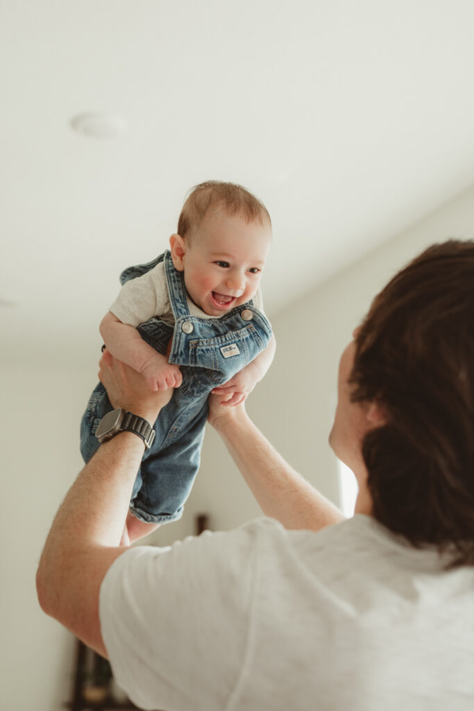 dad holds up baby and baby smiles big