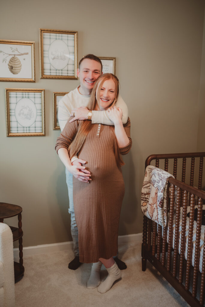 pregnant couple posing in their nursery
