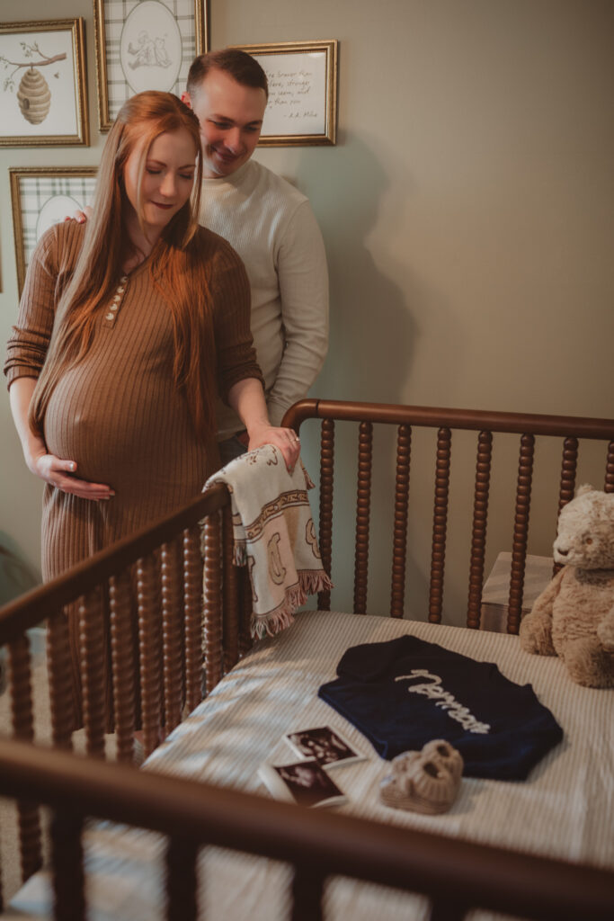 pregnant couple looking down into the crib that contains sentimental baby items