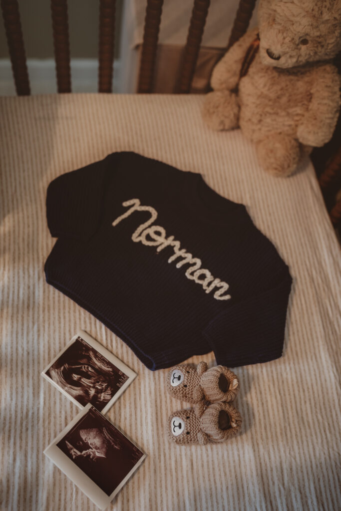 an embroidered sweater with their baby name and ultrasound photos inside the crib